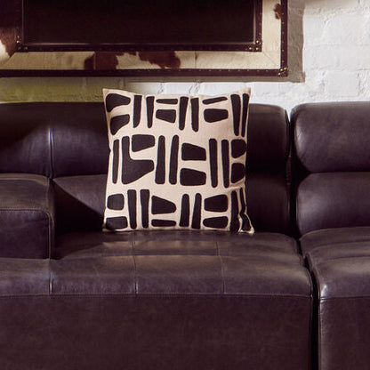 Living room with a brown leather sofa, decorative pillow, potted plant, and mirror.