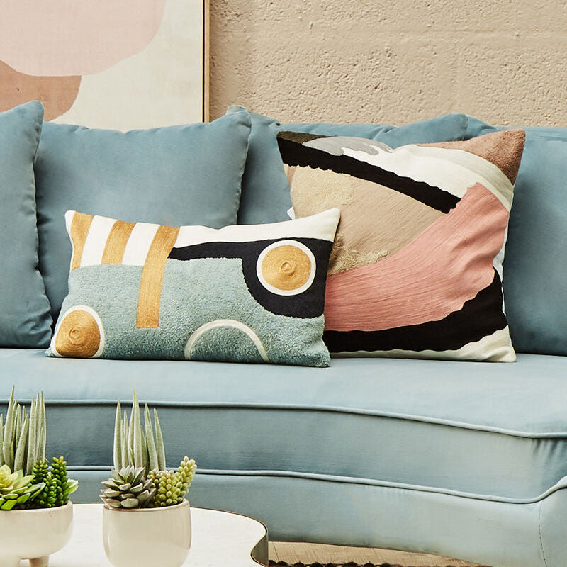 Light blue sofa with decorative pillows and a small round table with plants.