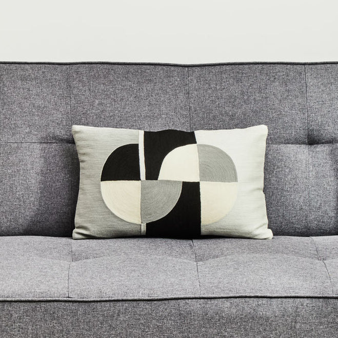 Gray sofa with a geometric-patterned pillow on a light background