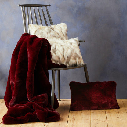 Chair with a red blanket and white pillows against a textured blue wall.