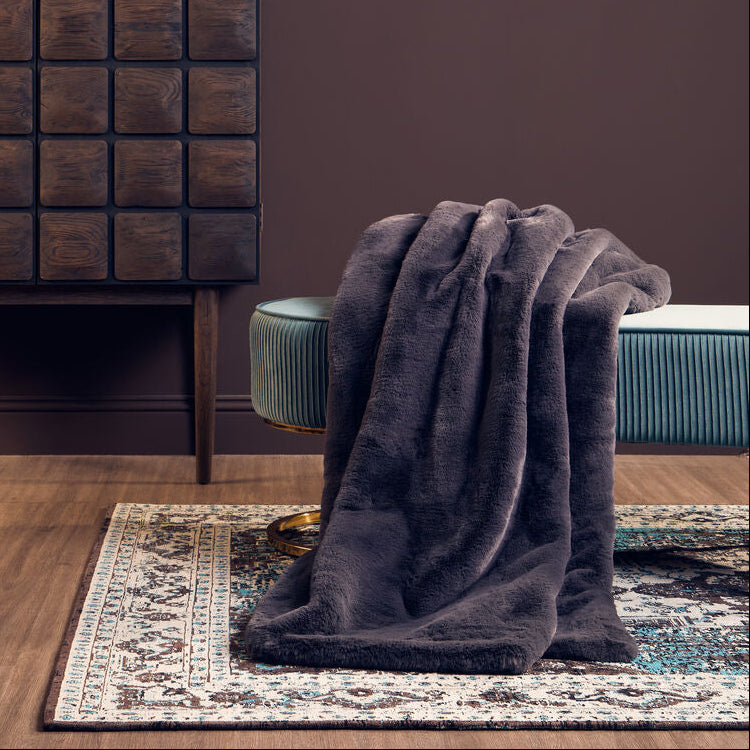 Room interior with a dark wooden cabinet, gray blanket, and green chair against a brown wall.
