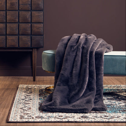 Room interior with a dark wooden cabinet, gray blanket, and green chair against a brown wall.