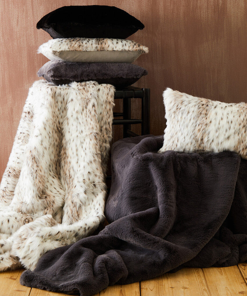 Stack of pillows and blankets on a wooden surface with a brown background