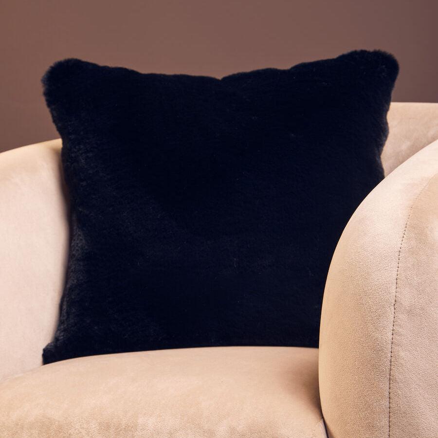 Black pillow on a beige armchair against a brown background