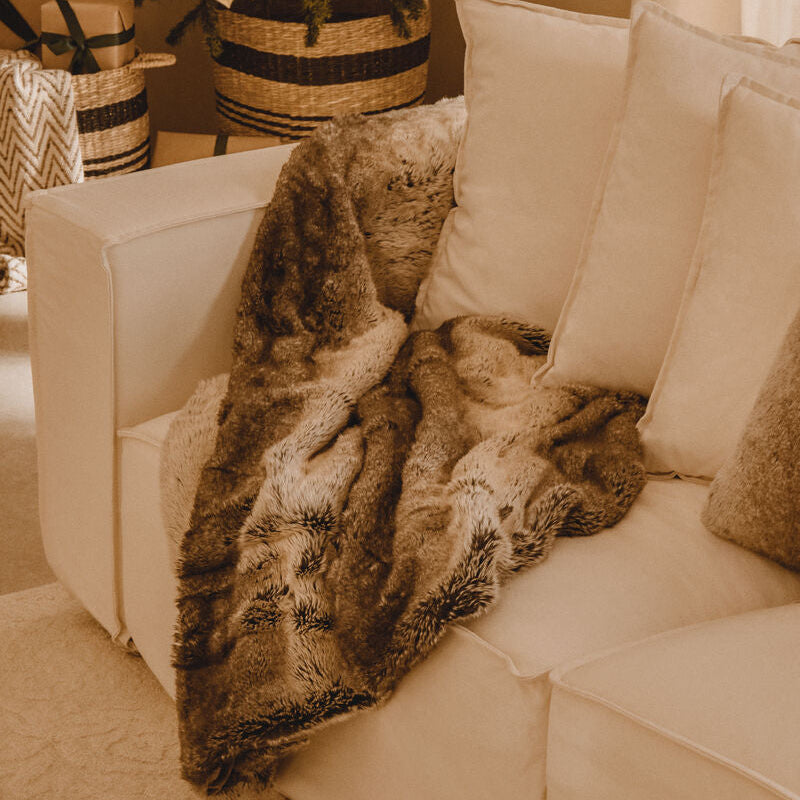 Beige sofa with a fur throw blanket in a living room setting.