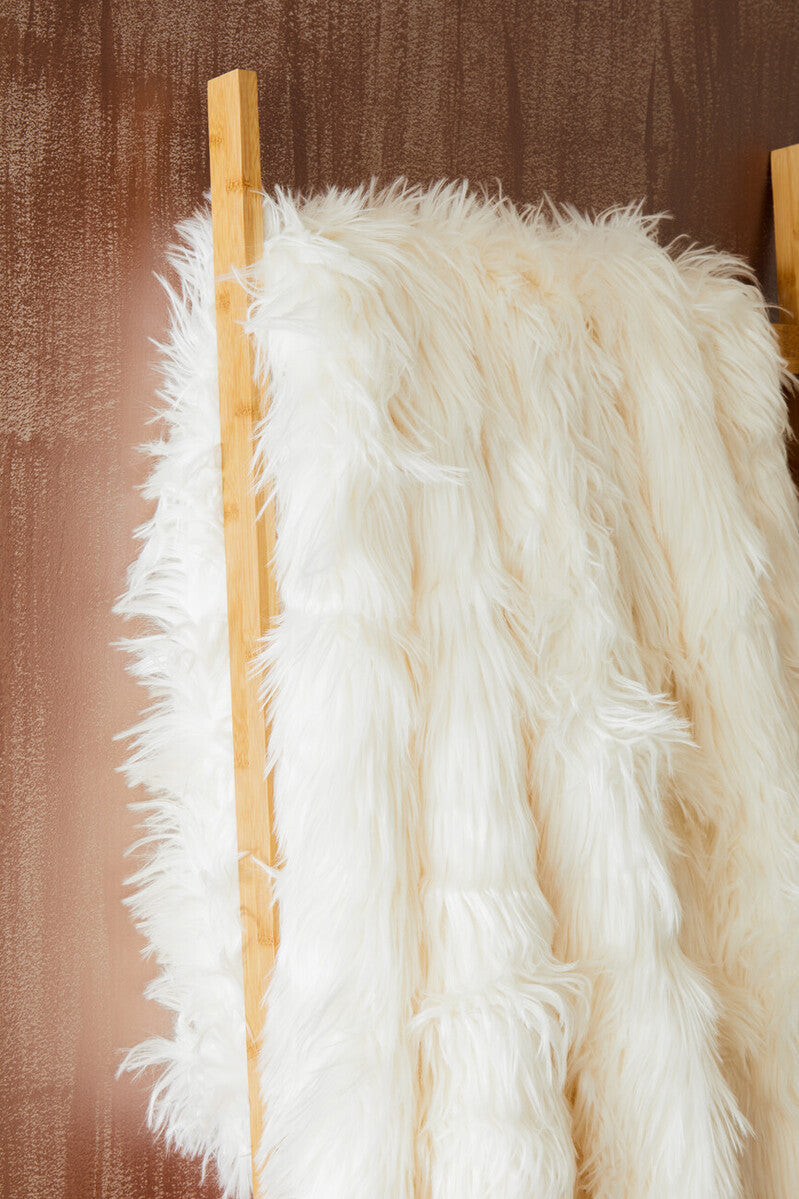 White fur throw draped over a wooden rod against a brown textured background