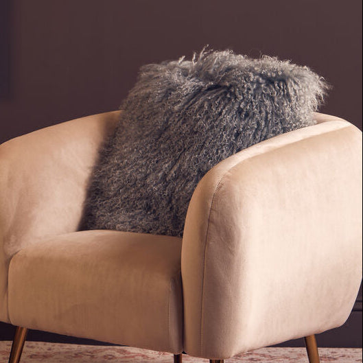 Beige armchair with a gray pillow against a dark purple wall