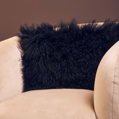 Black fluffy pillow on a beige armchair against a brown wall