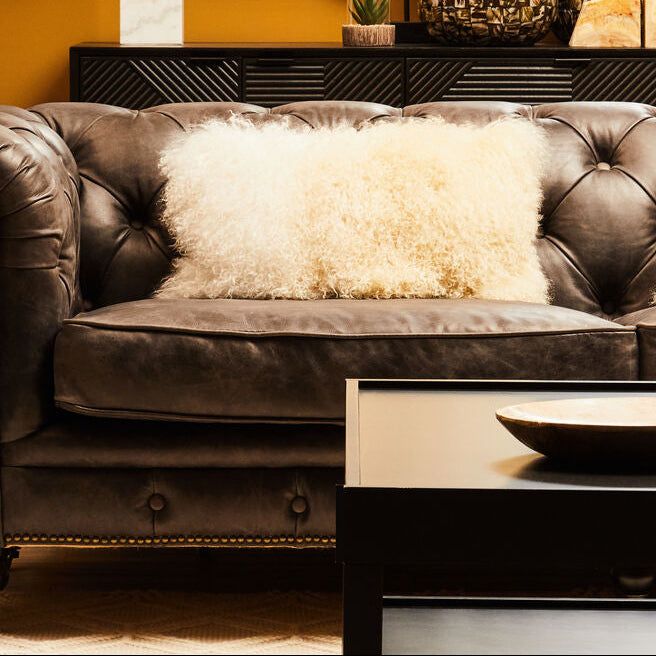 Living room with a brown leather sofa, decorative pillows, and a coffee table.