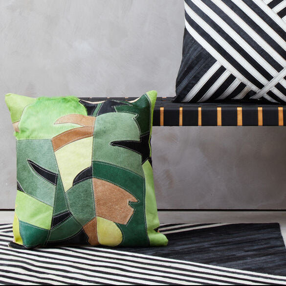 Decorative pillows on a bench with a geometric rug in the background