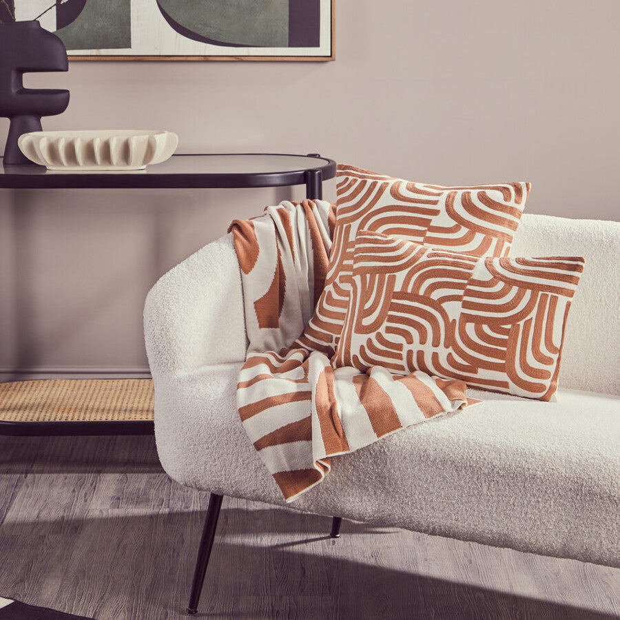 Living room with a gray sofa, patterned cushions, and abstract art on the wall.