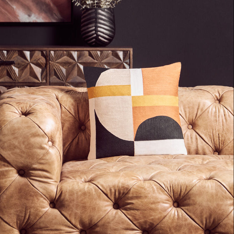Brown tufted sofa with a decorative pillow in a stylish room.