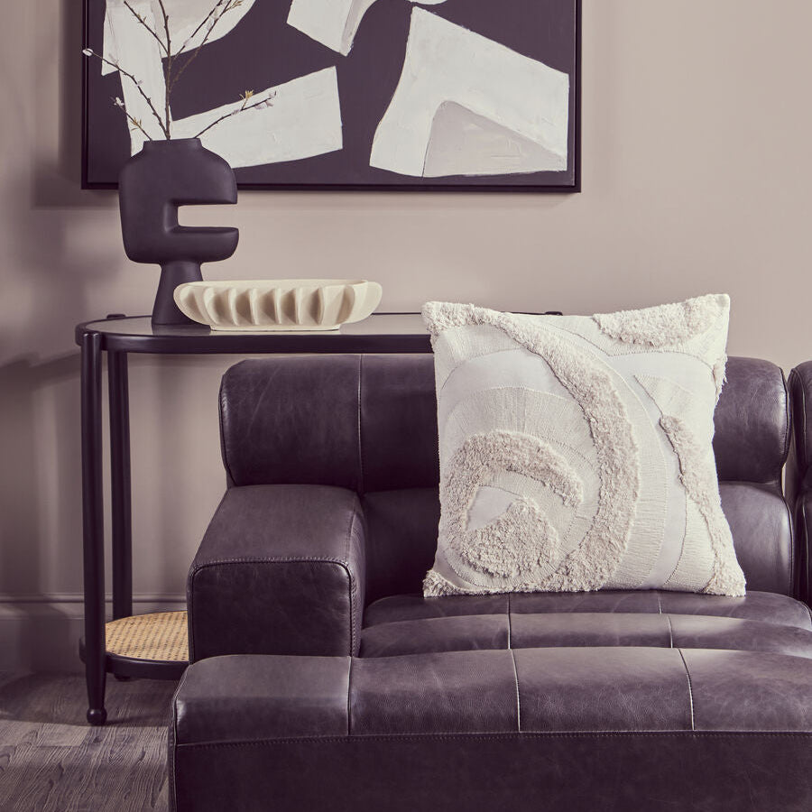 Living room with a gray sofa, abstract art, and decorative items.