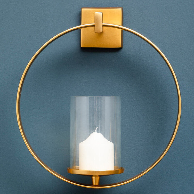 Gold wall sconce with a candle against a blue background