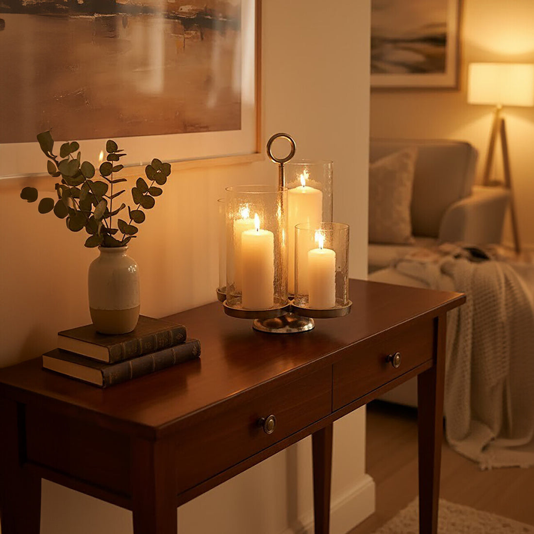 Candlelit table setting with candles, books, and a plant in a cozy living room.