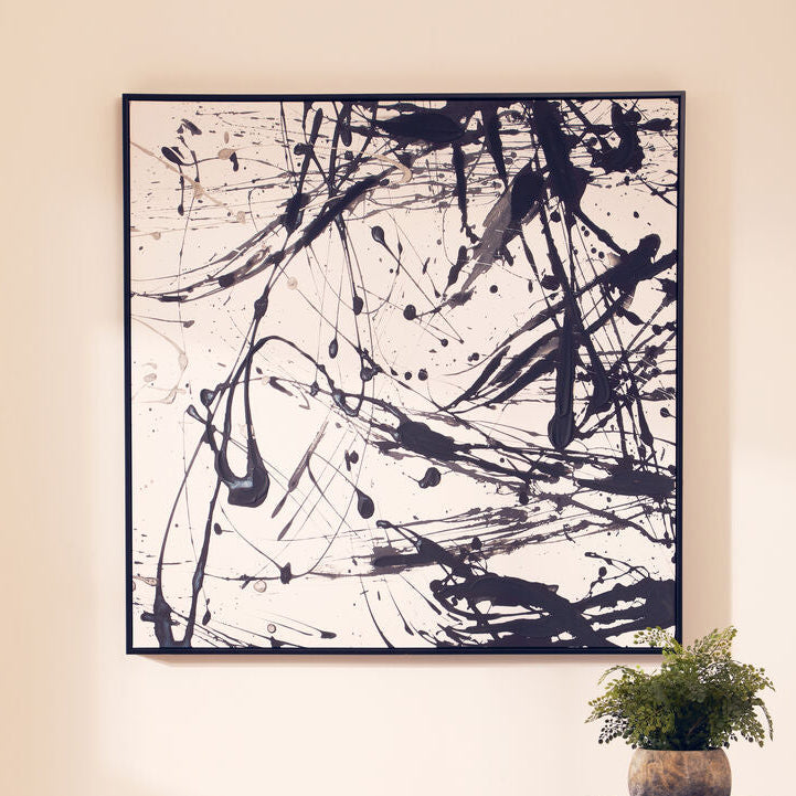 Abstract black and white painting on a wall above a stool and side table.