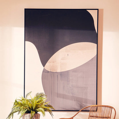 Wicker chair and side tables with a plant against a wall with abstract art