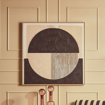 A styled interior scene with a beige paneled wall, a framed abstract artwork above a striped armchair, a ribbed round coffee table, and decorative glass bottles on a side table.