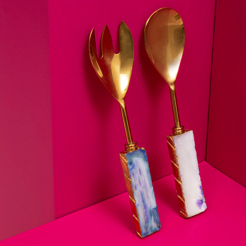 Gold fork and spoon with marble handles on a pink background