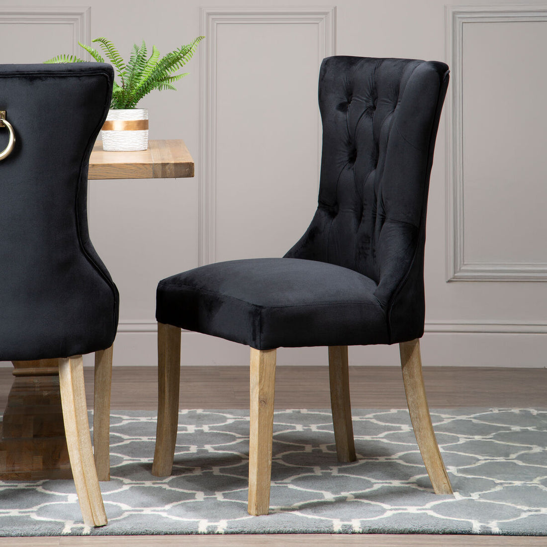 Black upholstered chair with wooden legs in a room setting.