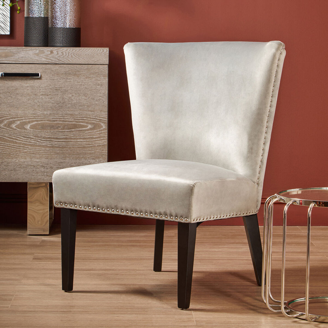 Beige upholstered chair with dark legs in a room with wooden floor and furniture.