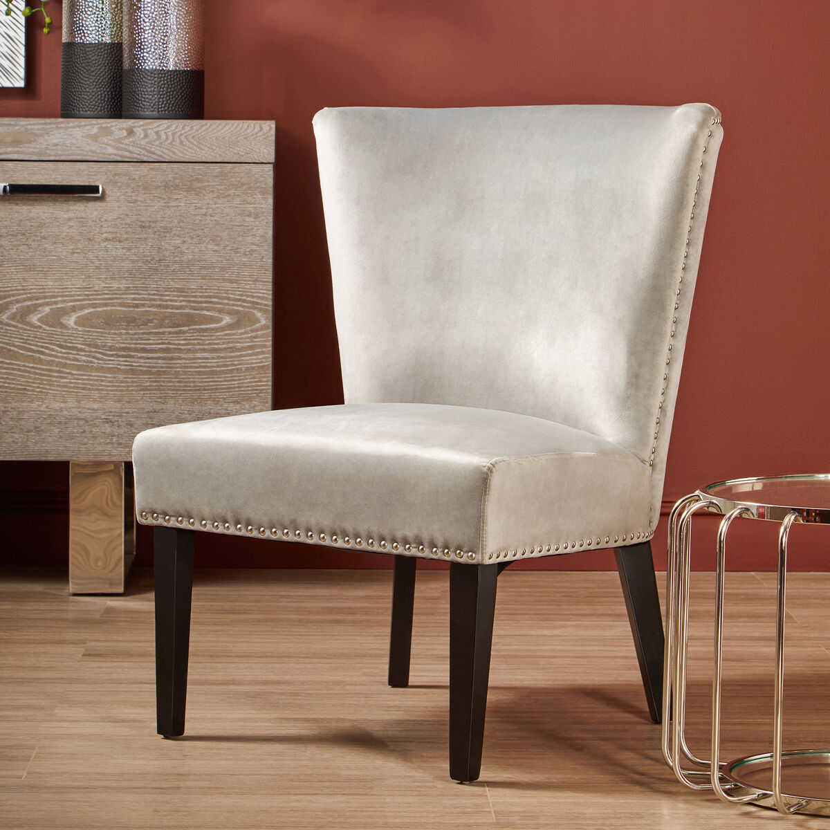 Beige upholstered chair with dark legs in a room with wooden floor and furniture.