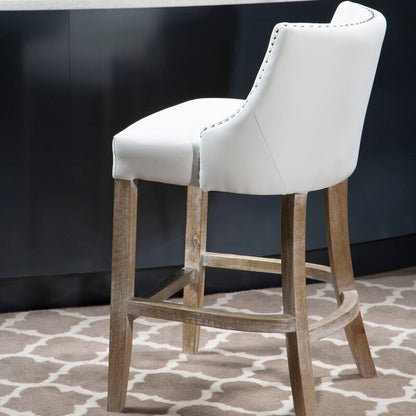White bar stool with wooden legs in front of a dark wall and light gray countertop.