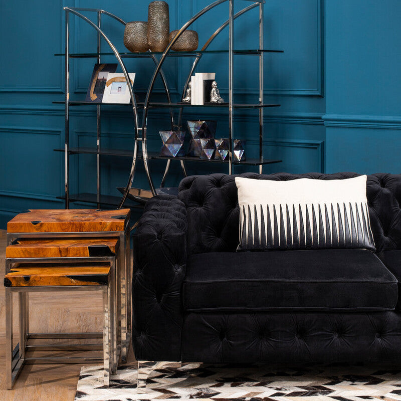 Black sofa with a decorative pillow in a room with a blue wall and wooden floor.