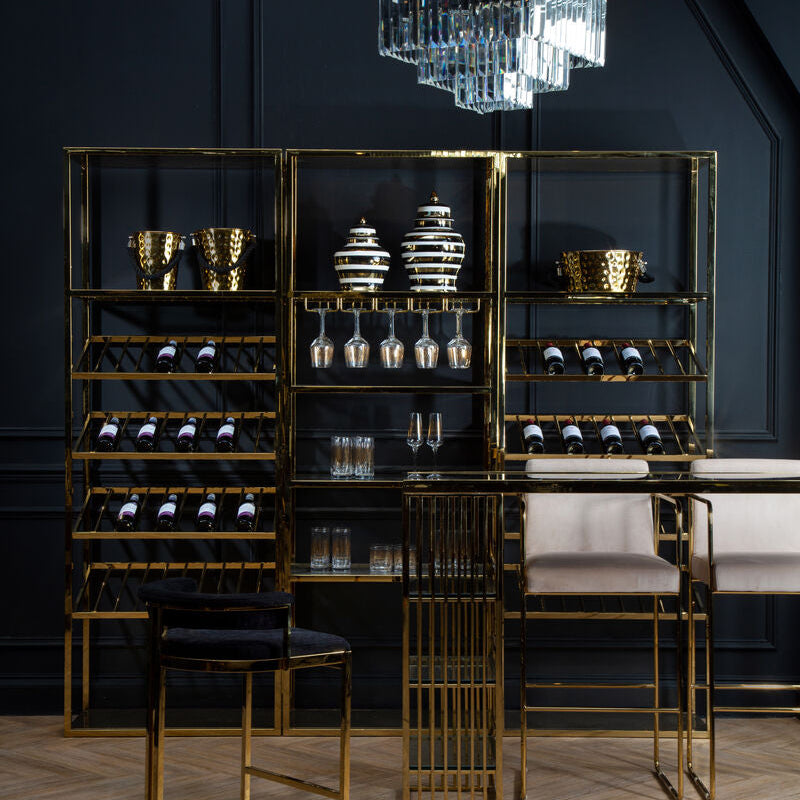 Modern bar setup with gold shelves, chairs, and a chandelier against a dark wall.