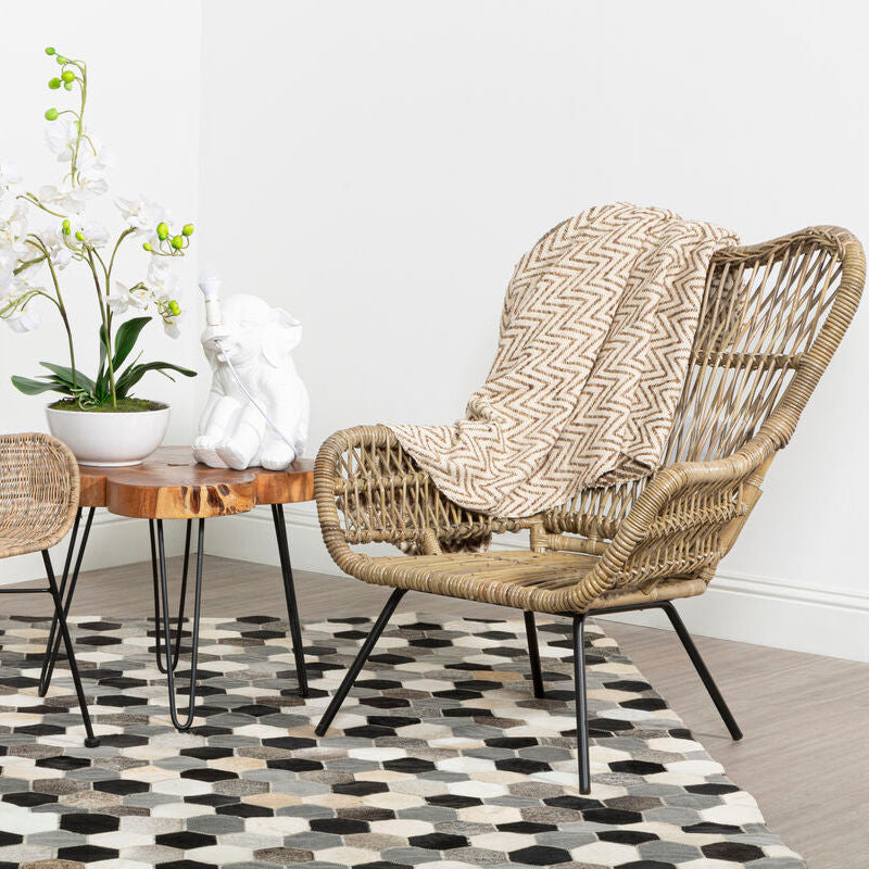 Wicker chair with a patterned cover in a room with a wooden table and decorative items.