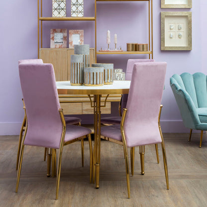 Dining room with pink chairs, gold table, and decorative shelves against a purple wall.