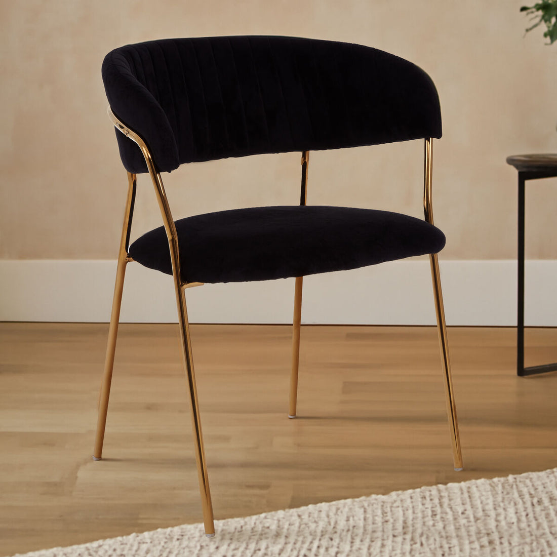 Black upholstered chair with gold legs on a wooden floor.
