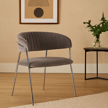 Gray chair with metal legs in a room with a beige wall, framed art, and a small table with a vase.