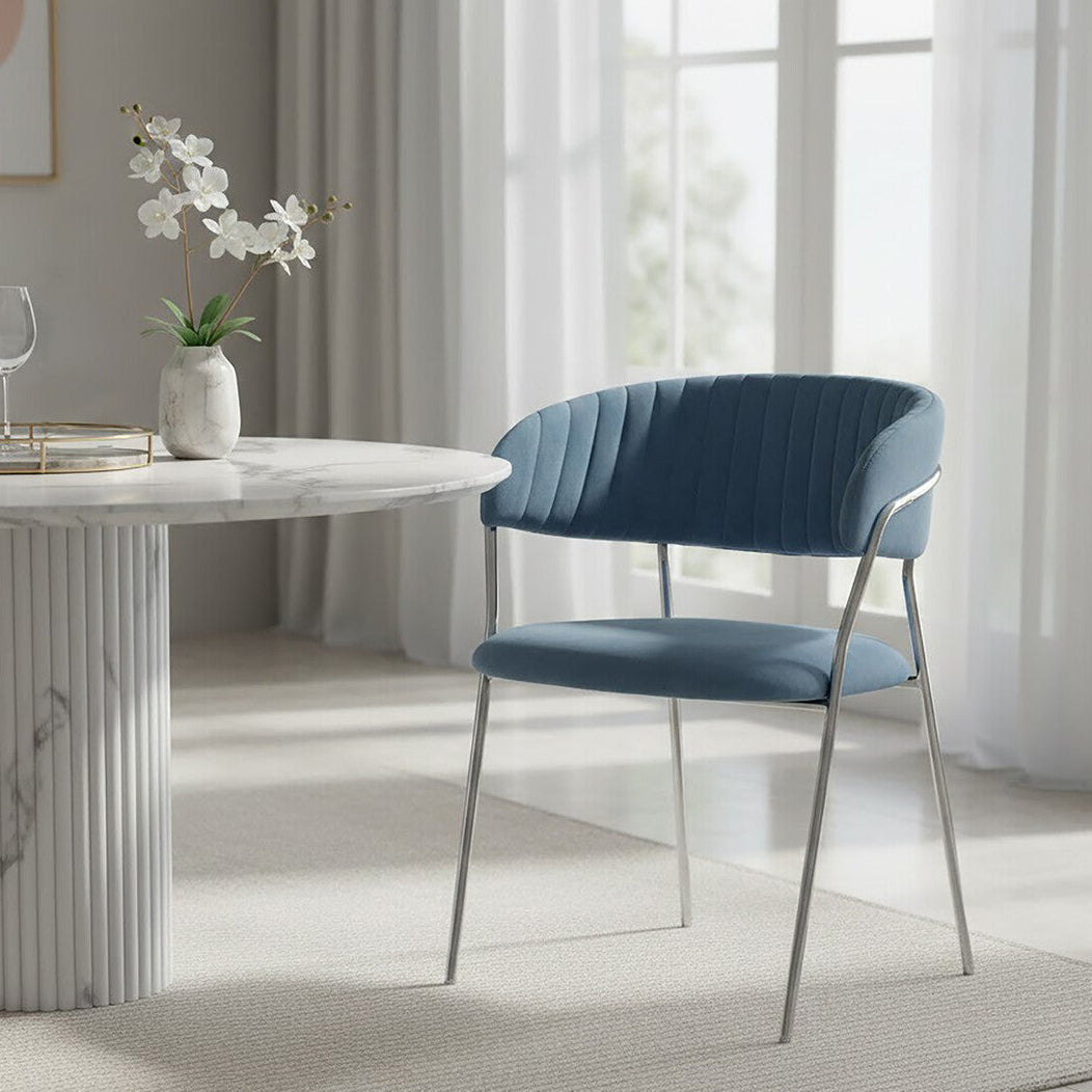 Blue chair in a modern dining room with marble table and white curtains.