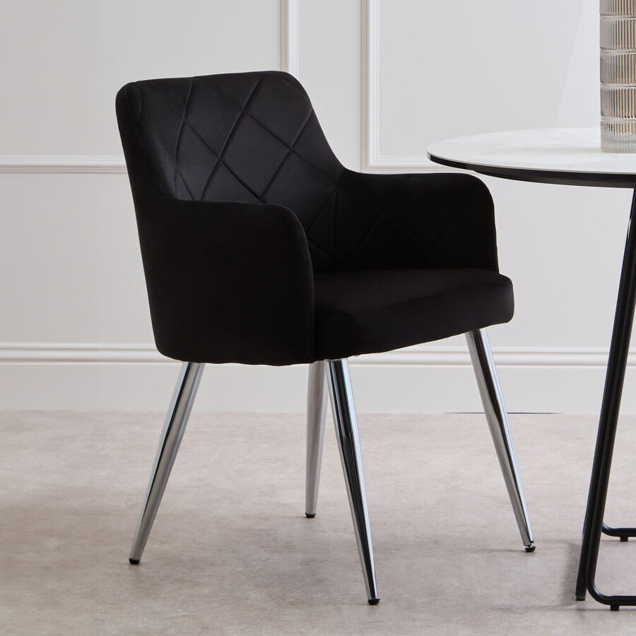 Black upholstered chair with chrome legs in a minimalistic room.