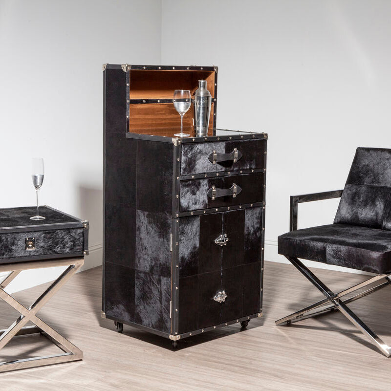 Black leather furniture set including a cabinet, side table, and chair on a light wood floor.