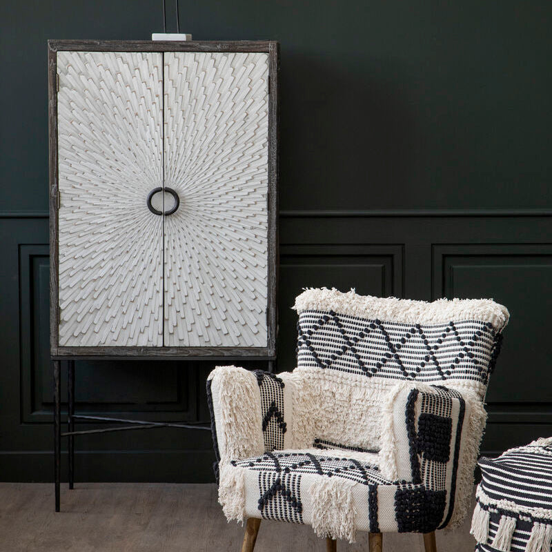Chair with patterned cushions in a room with dark walls and decorative elements.