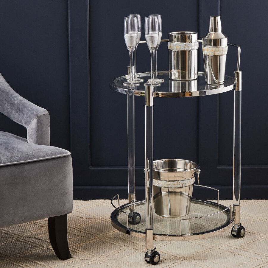 Bar cart with cocktail-making equipment against a dark blue wall.