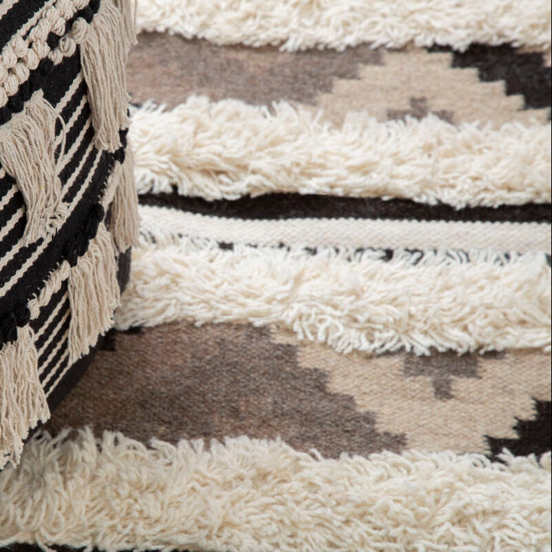 Close-up of a textured black and white patterned rug with tassels.