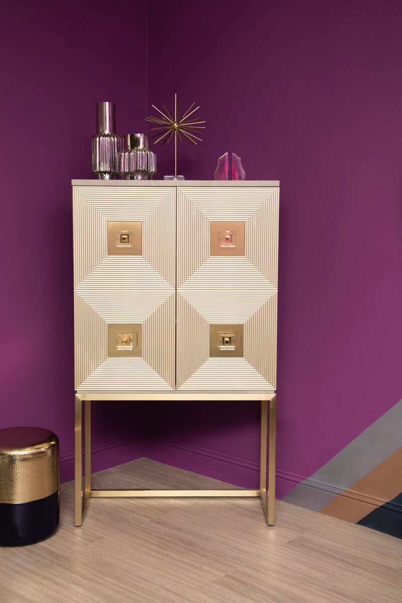 Decorative cabinet with geometric design against a purple wall