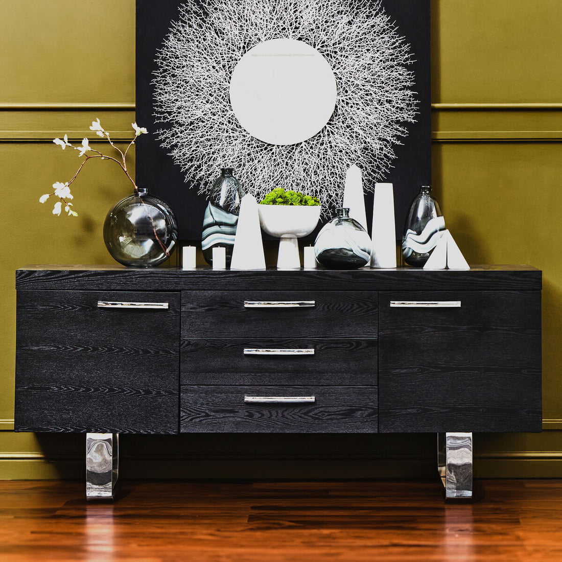 Black dresser with decorative items against a green wall