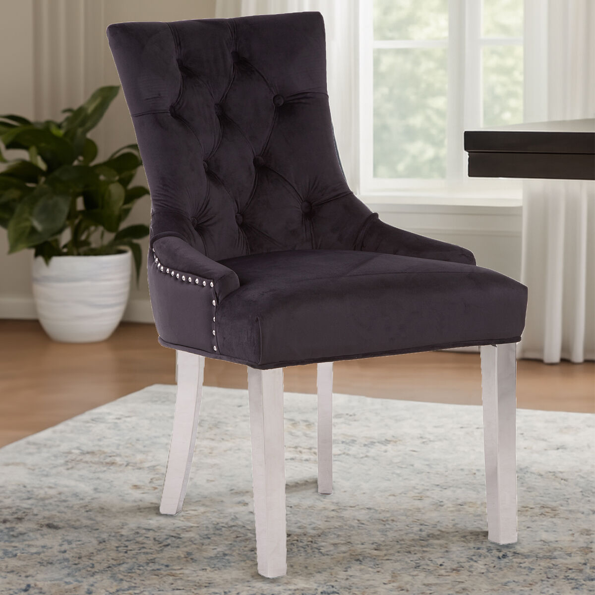 Dark purple upholstered chair with white legs in a room setting.