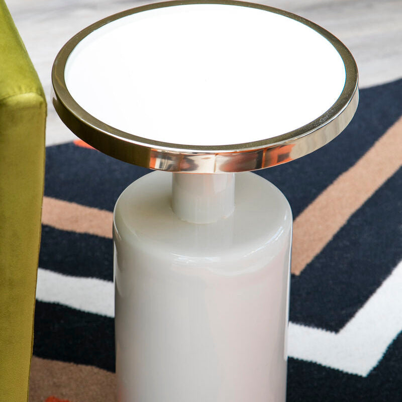 Small round table with a white base and gold rim on a patterned rug
