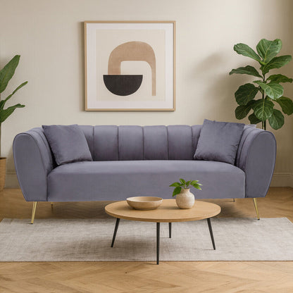 Gray sofa in a living room with a round wooden coffee table, plants, and abstract art on the wall.