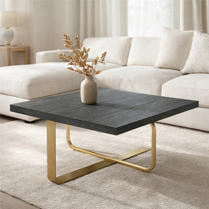 Modern coffee table with dark surface and gold legs in a living room setting.