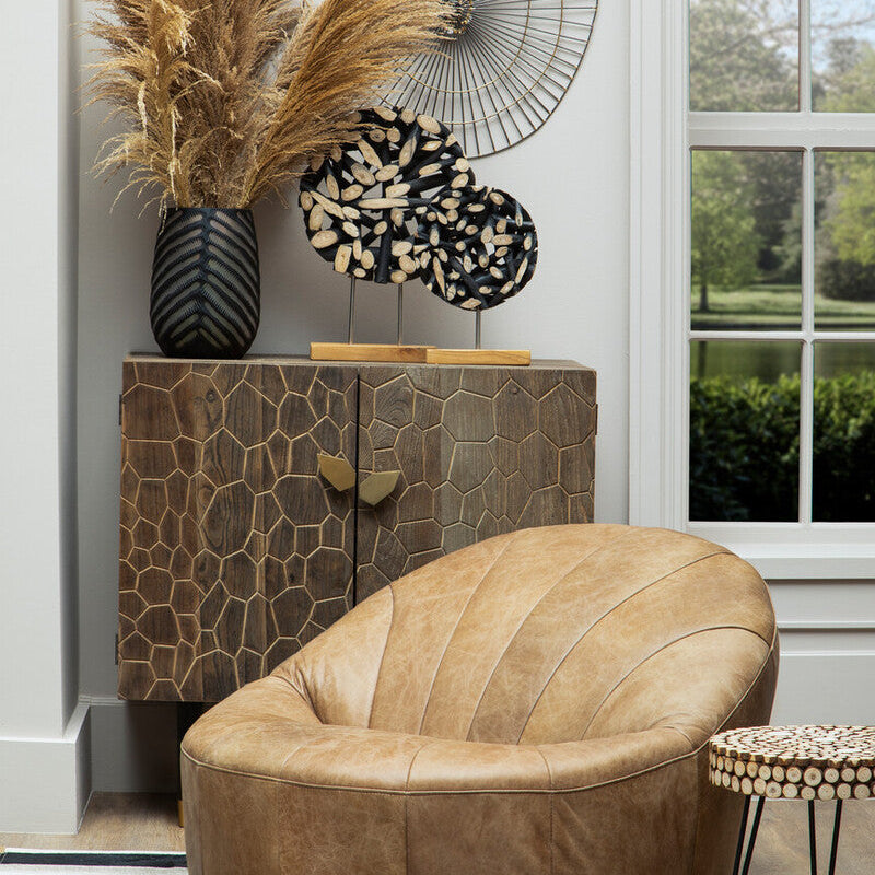 Modern interior with a brown leather chair, textured cabinet, and decorative elements.