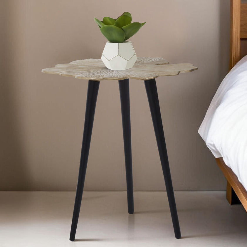 Small round table with a plant next to a bed in a bedroom setting