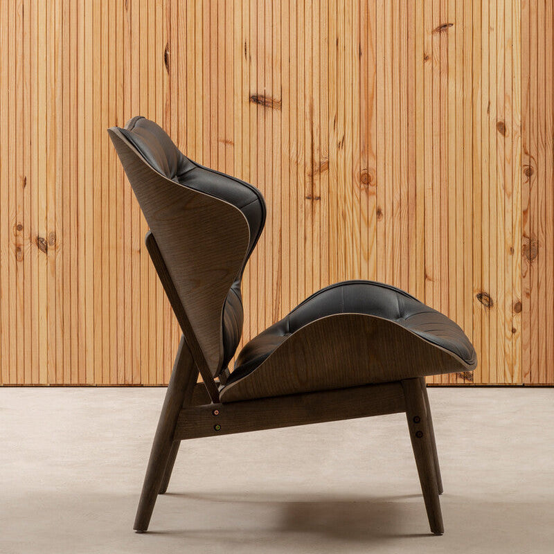Modern black chair against a wooden wall