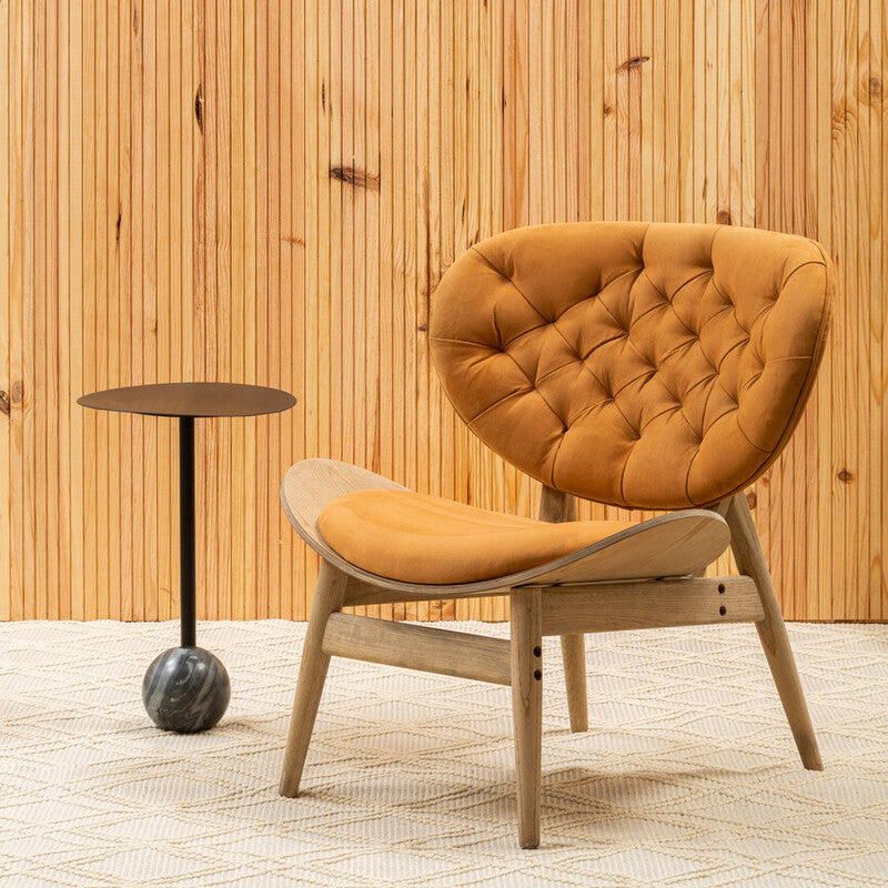 Orange chair with wooden legs against a wooden paneled wall.
