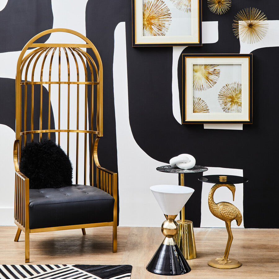 Decorative interior setting with gold birdcage chair, black and white rug, and wall art.